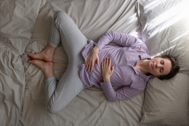 woman on bed practicing mother/butterfly yoga pose